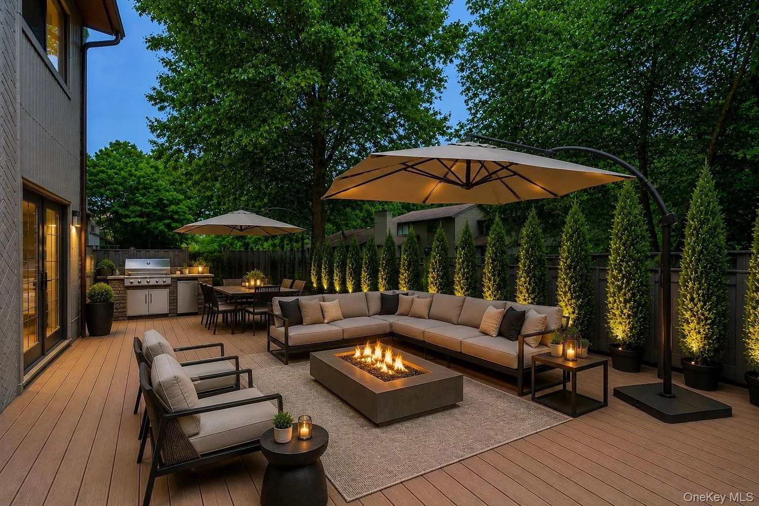 Expansive wood-finish deck with an integrated outdoor kitchen featuring a built-in grill, a separate dining area, and a dedicated lounge space with a fire pit Expansive wood-finish deck with an integrated outdoor kitchen featuring a built-in grill, a separate dining area, and a dedicated lounge space with a fire pit