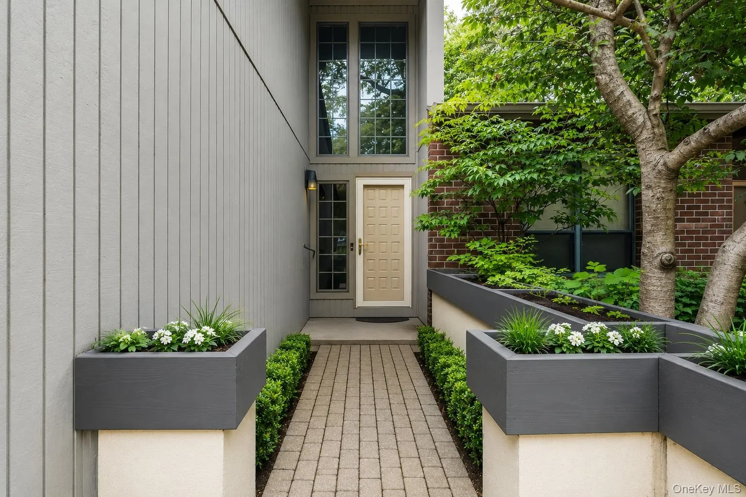 Exterior showcasing board and batten siding, a paneled entry door, upper transom windows, and a paver pathway Exterior showcasing board and batten siding, a paneled entry door, upper transom windows, and a paver pathway