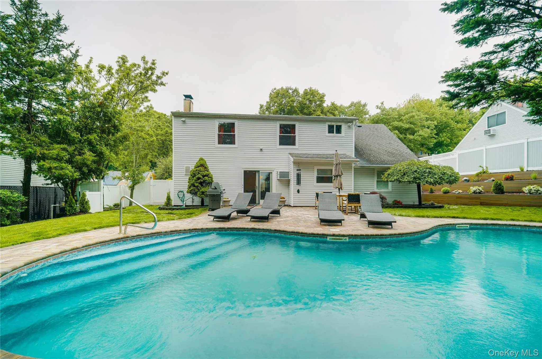 Resort-style pool surrounded by a paver patio and mature landscaping Resort-style pool surrounded by a paver patio and mature landscaping