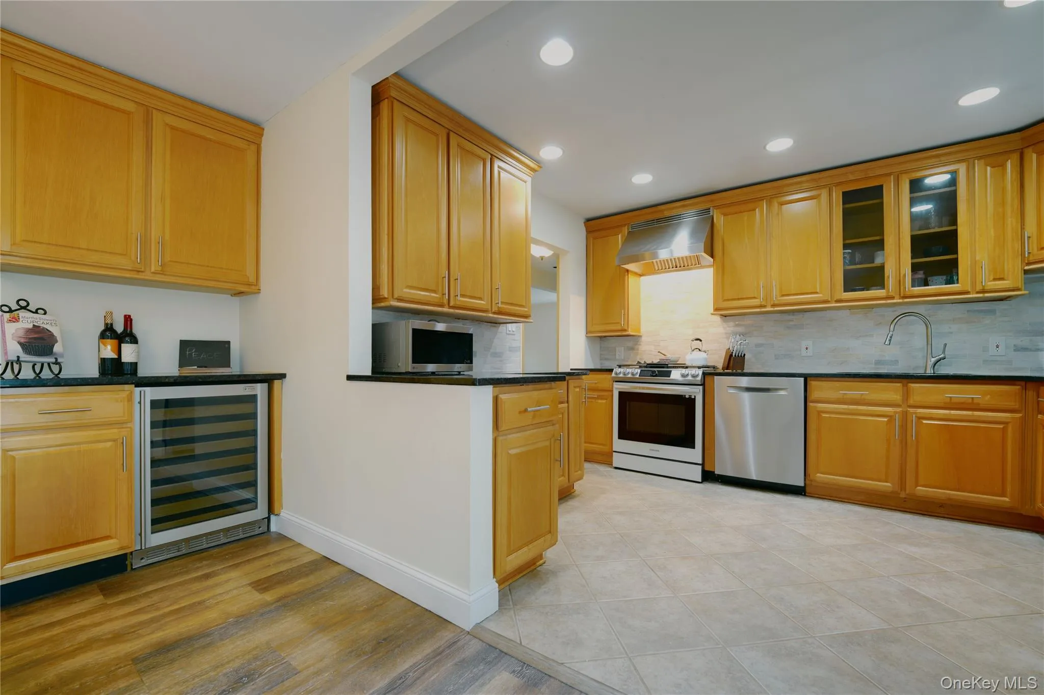 Kitchen featuring light wood cabinetry, dark countertops, stainless steel appliances, and recessed lighting Kitchen featuring light wood cabinetry, dark countertops, stainless steel appliances, and recessed lighting