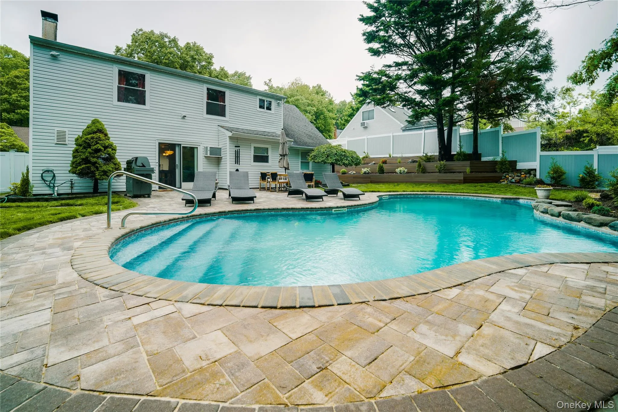 Resort-style pool surrounded by a paver patio and mature landscaping Resort-style pool surrounded by a paver patio and mature landscaping