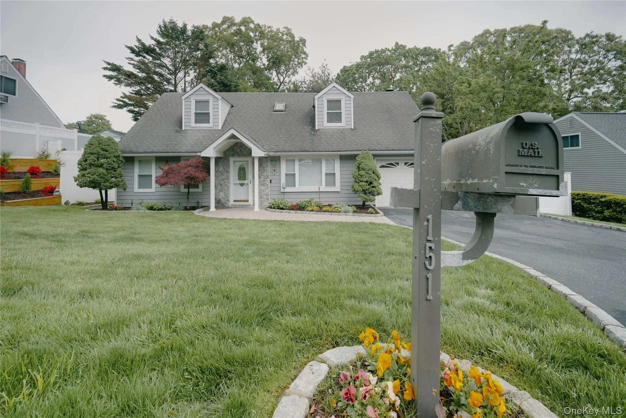 Vinyl Gray siding exterior with dormer windows, an integrated garage, and a large paved drivewayts Vinyl Gray siding exterior with dormer windows, an integrated garage, and a large paved drivewayts