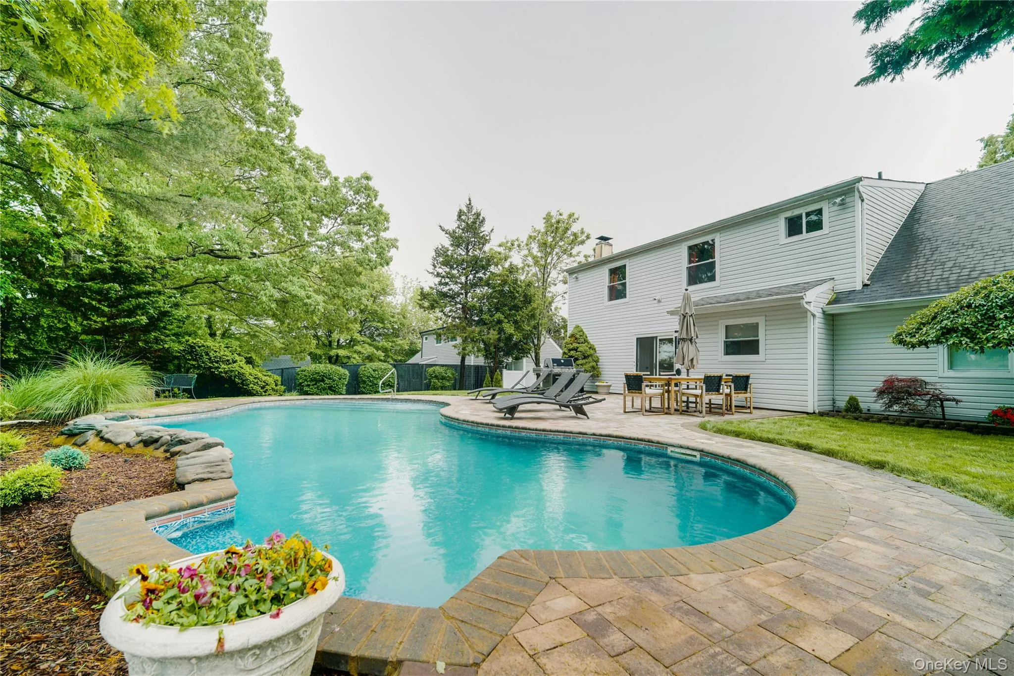 Resort-style pool surrounded by a paver patio and mature landscaping Resort-style pool surrounded by a paver patio and mature landscaping