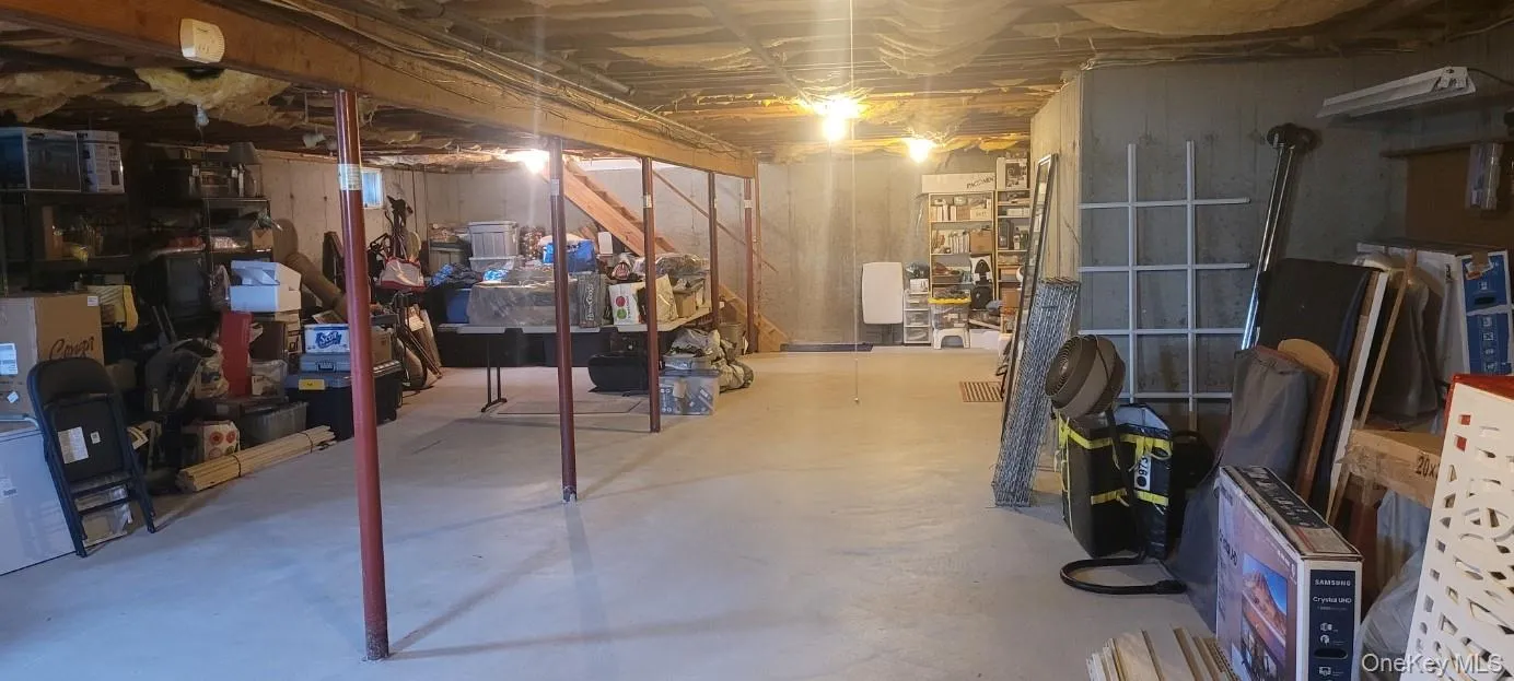 Unfinished basement with concrete flooring, exposed high ceiling joists, and structural support beams Unfinished basement with concrete flooring, exposed high ceiling joists, and structural support beams