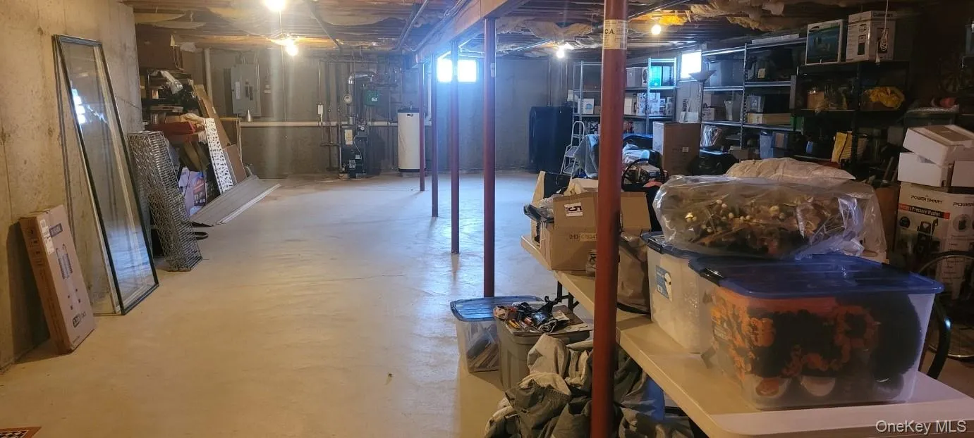 Expansive unfinished basement featuring a concrete floor, exposed high ceiling joists, and structural support columns Expansive unfinished basement featuring a concrete floor, exposed high ceiling joists, and structural support columns