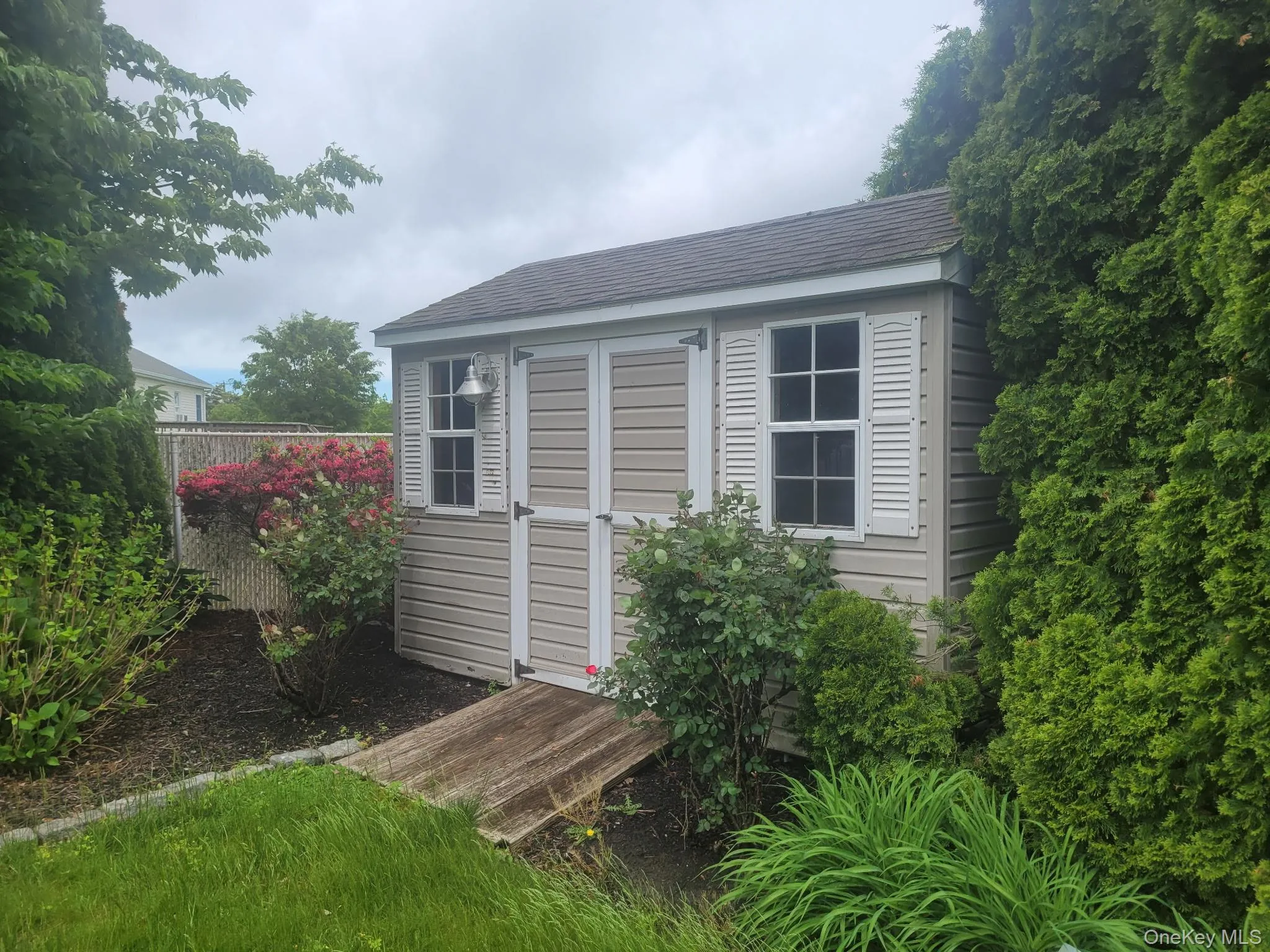 Detached storage shed with horizontal siding, louvered shutters, and a shingled roof Detached storage shed with horizontal siding, louvered shutters, and a shingled roof
