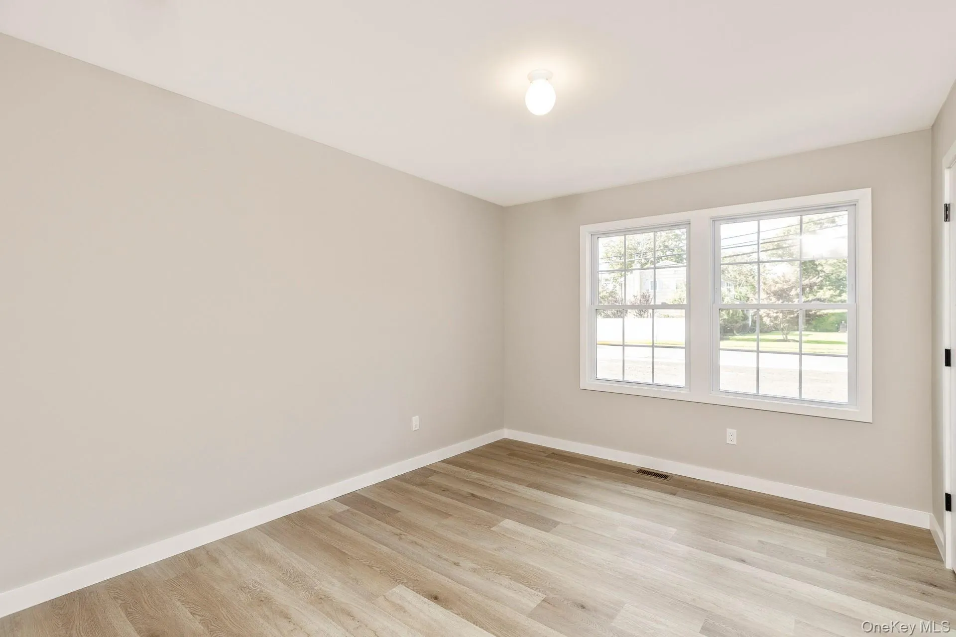 Spare room with baseboards and light wood-style floors Spare room with baseboards and light wood-style floors