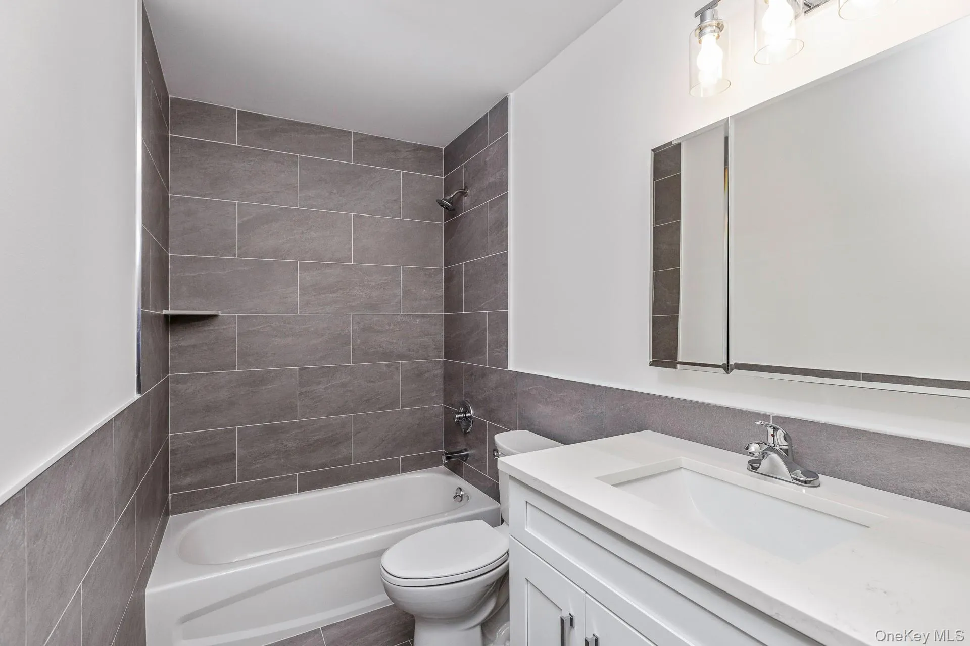 Bathroom featuring shower / bathtub combination, vanity, and tile walls Bathroom featuring shower / bathtub combination, vanity, and tile walls