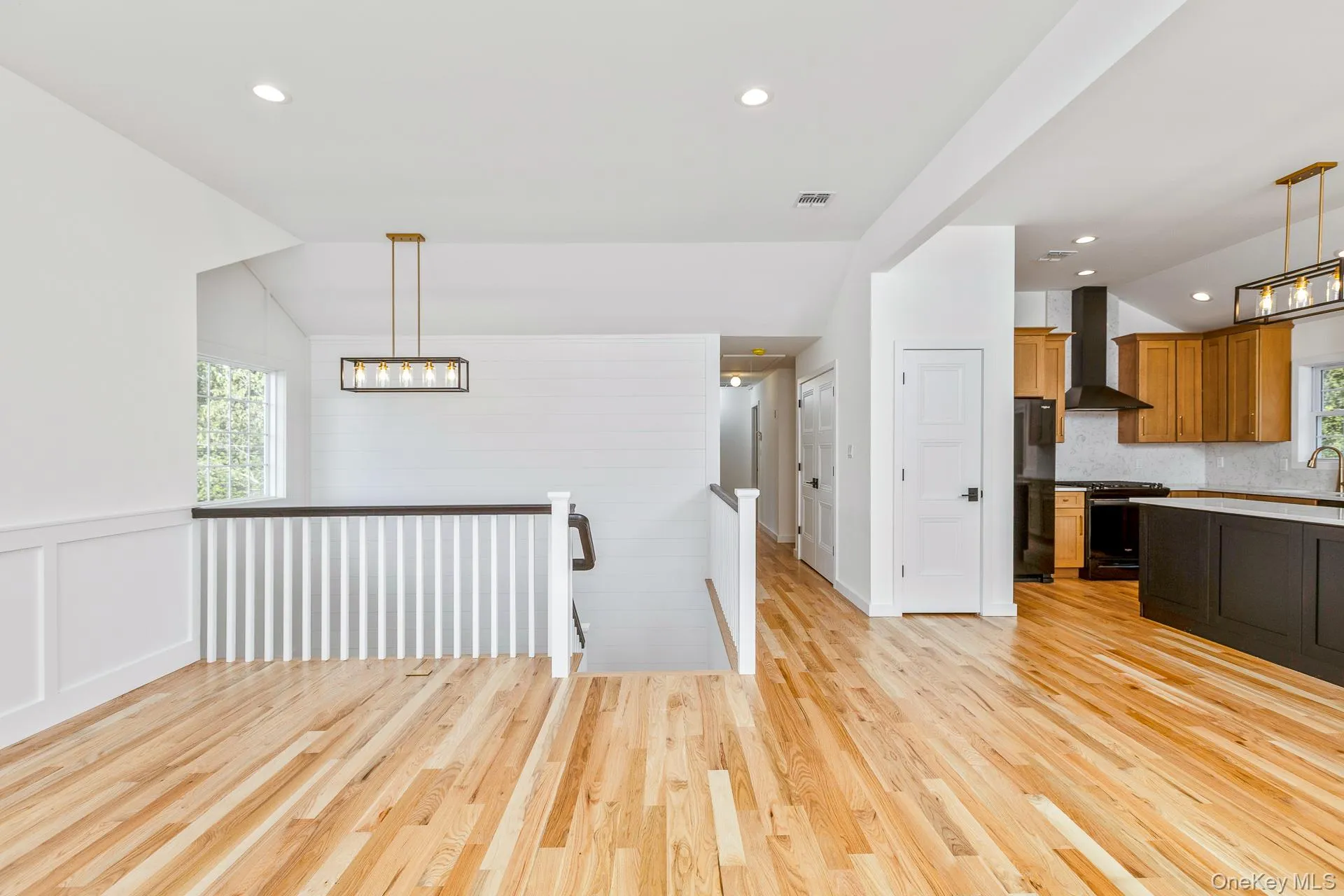 Kitchen with hanging light fixtures, brown cabinetry, light wood-style floors, recessed lighting, and black appliances Kitchen with hanging light fixtures, brown cabinetry, light wood-style floors, recessed lighting, and black appliances