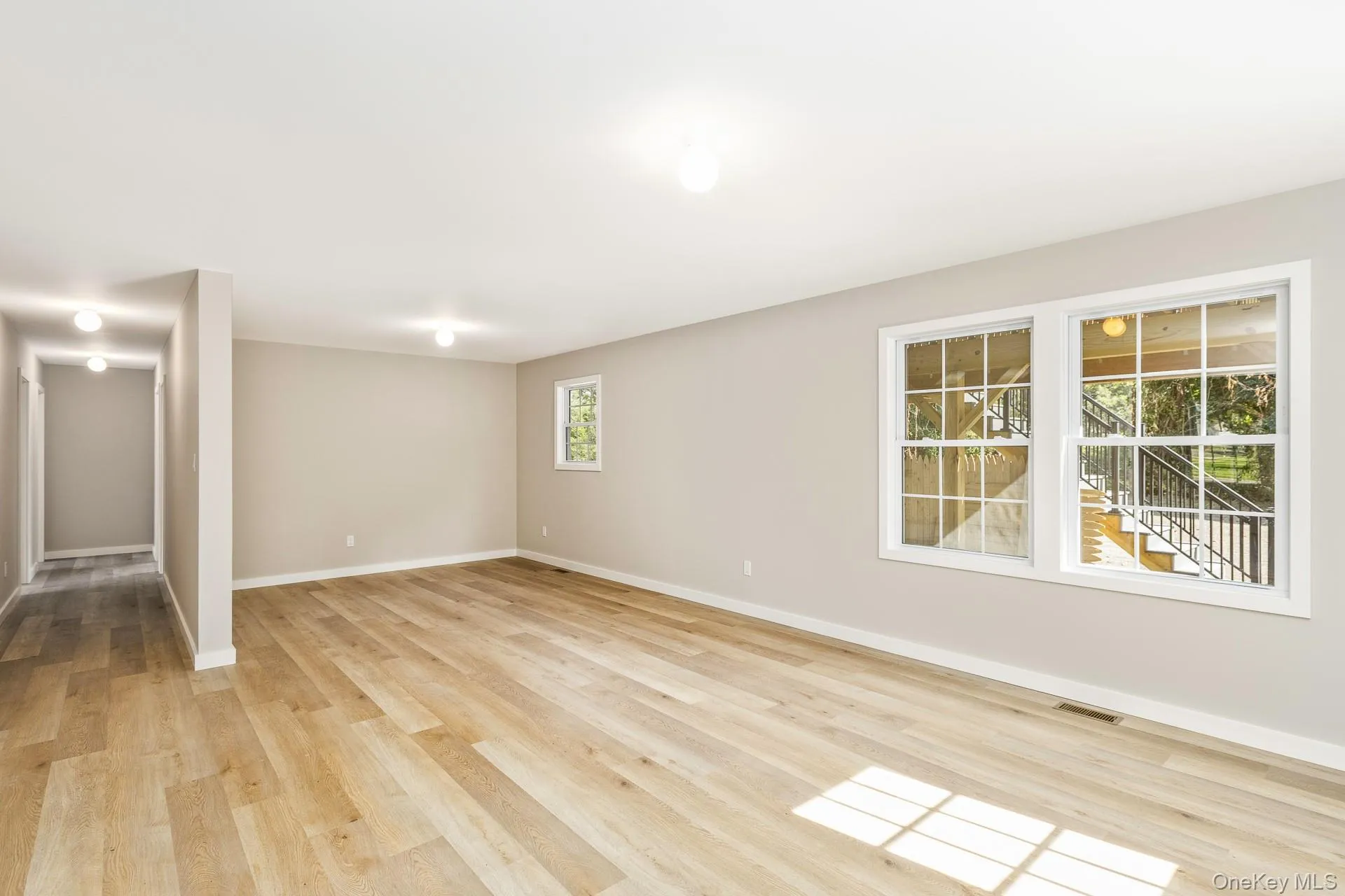 Unfurnished living room featuring light wood-style flooring and baseboards Unfurnished living room featuring light wood-style flooring and baseboards