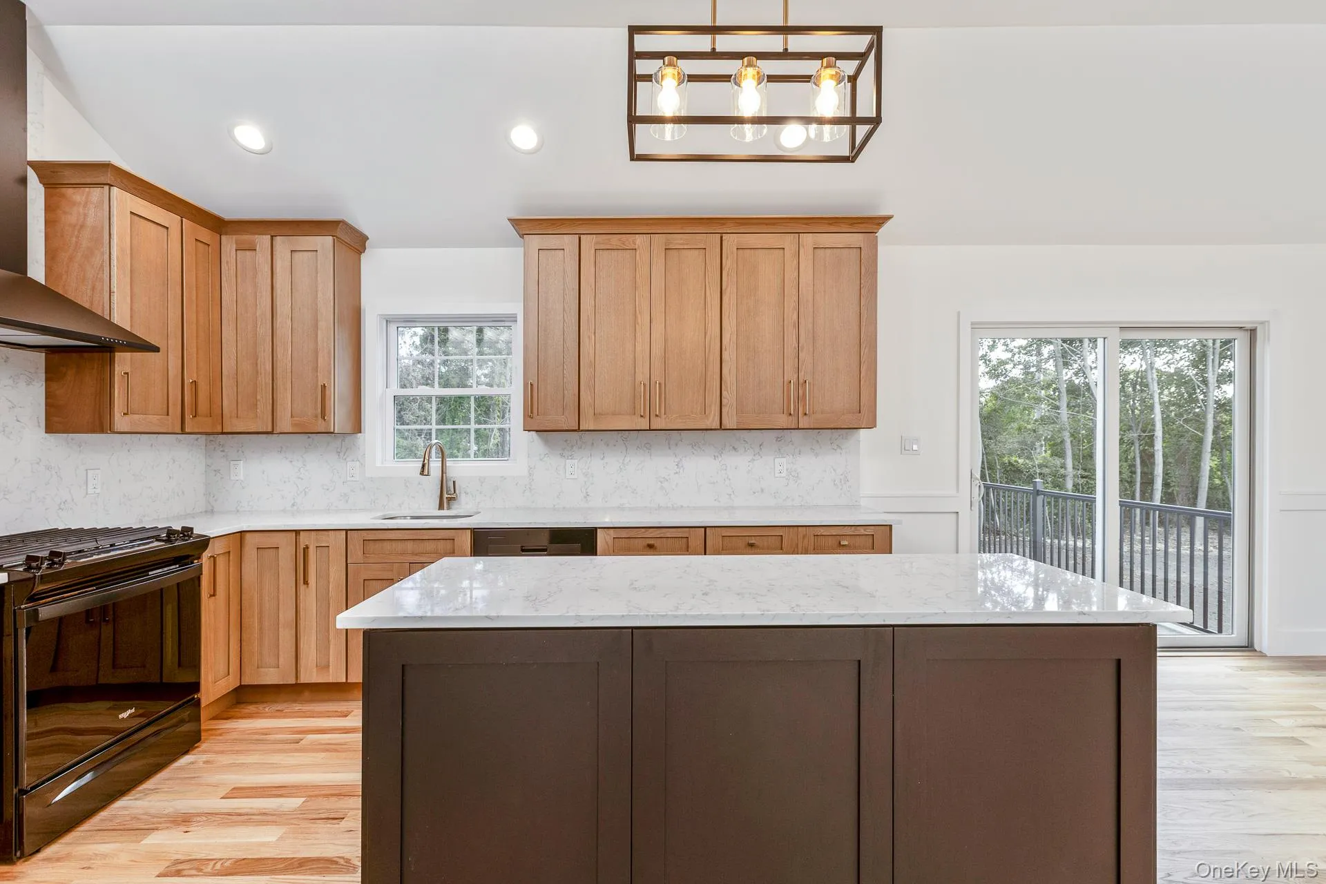 Kitchen with black range oven, wall chimney exhaust hood, recessed lighting, tasteful backsplash, and light stone counters Kitchen with black range oven, wall chimney exhaust hood, recessed lighting, tasteful backsplash, and light stone counters