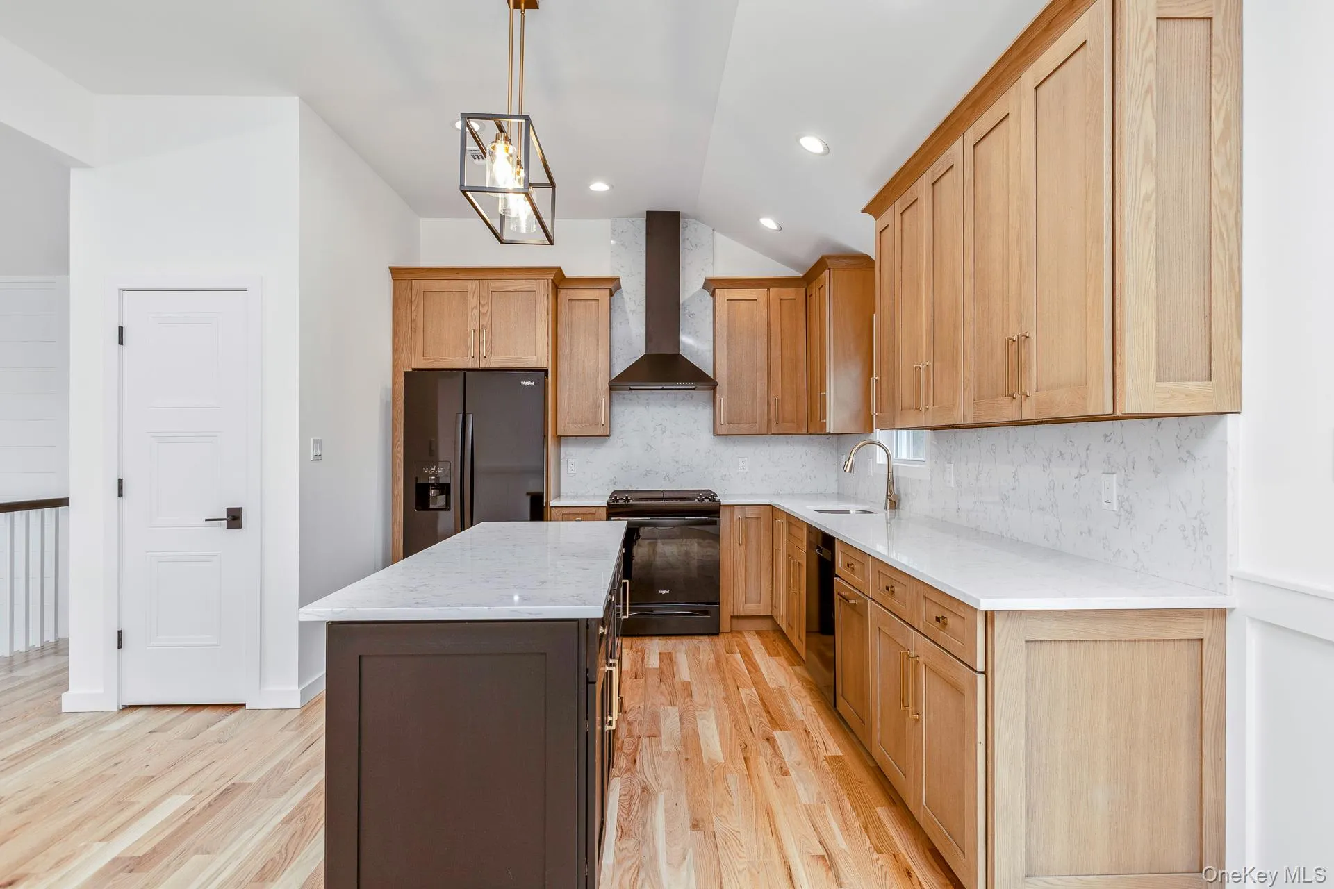 Kitchen featuring pendant lighting, light stone counters, a kitchen island, vaulted ceiling, and backsplash Kitchen featuring pendant lighting, light stone counters, a kitchen island, vaulted ceiling, and backsplash