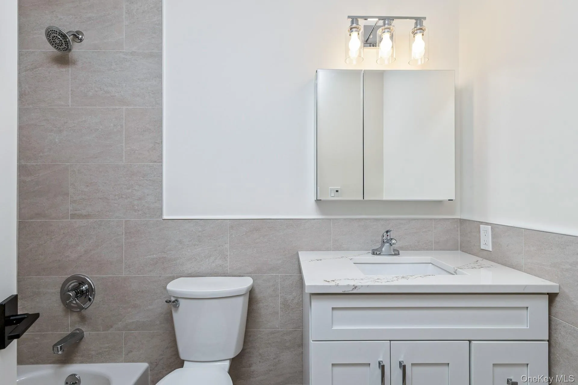 Bathroom with shower combination, vanity, and tile walls Bathroom with shower combination, vanity, and tile walls