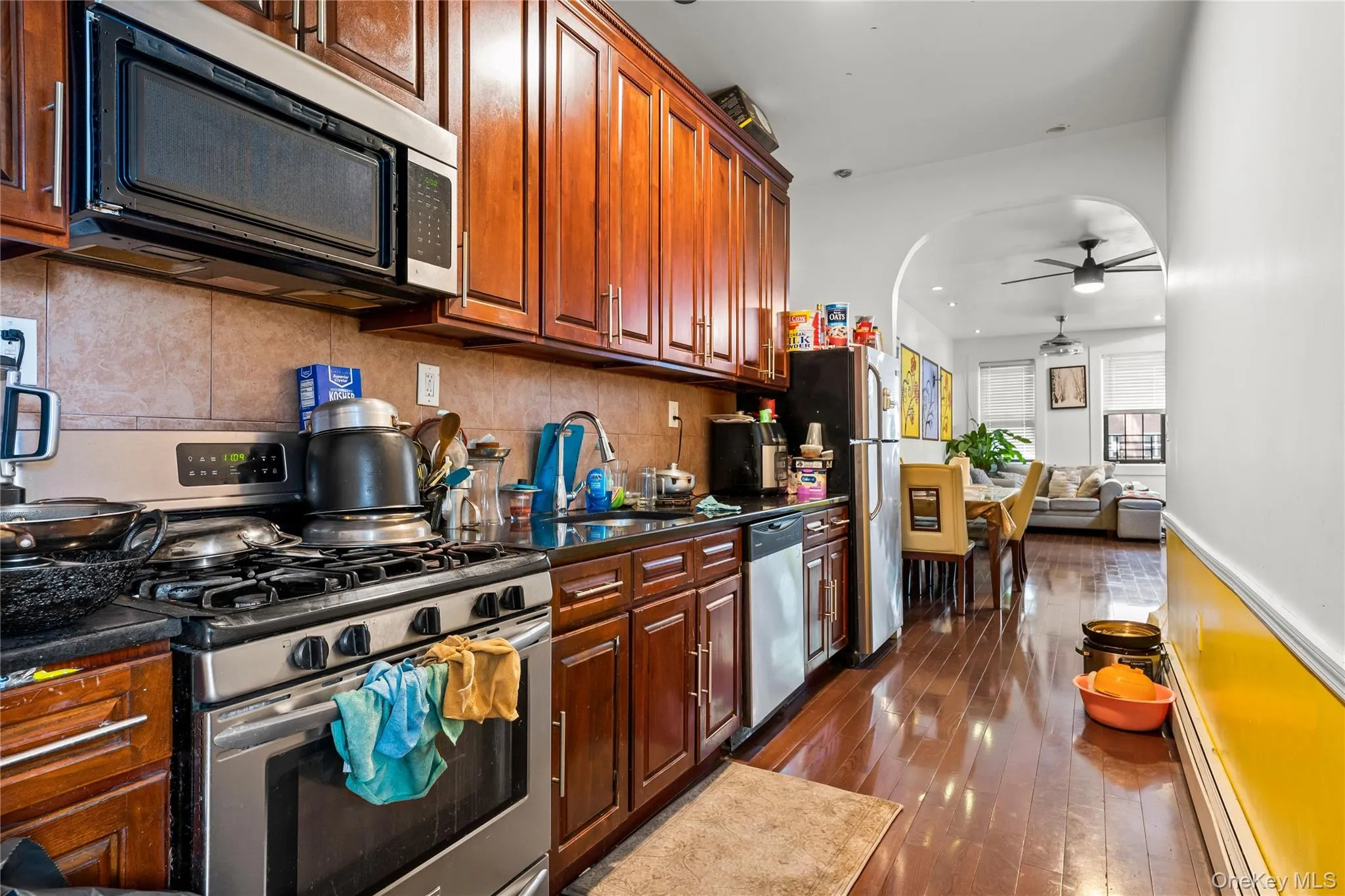 Kitchen featuring wood-finish cabinetry, stainless steel appliances, dark countertops, and a tiled backsplash Kitchen featuring wood-finish cabinetry, stainless steel appliances, dark countertops, and a tiled backsplash