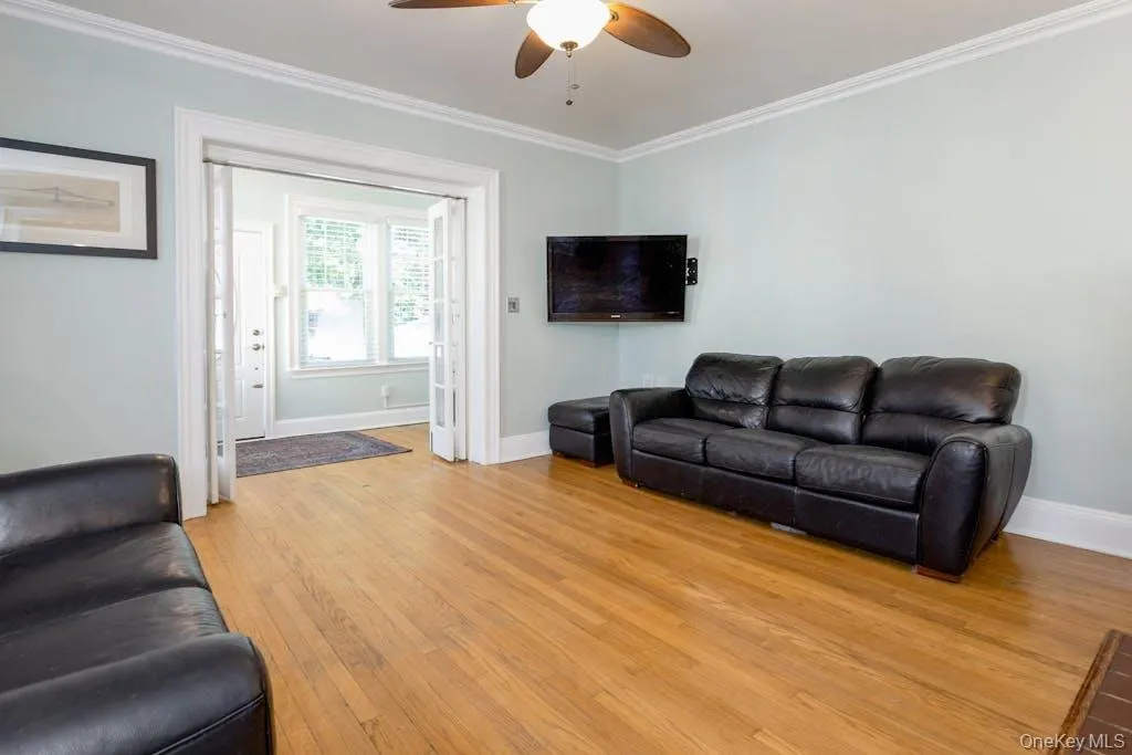 Living room with ceiling fan, light wood-type flooring, and ornamental molding Living room with ceiling fan, light wood-type flooring, and ornamental molding