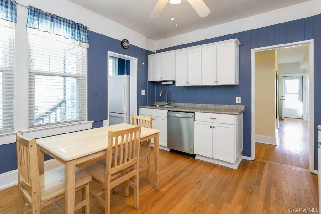 Kitchen with light hardwood / wood-style flooring, sink, white fridge, stainless steel dishwasher, and white cabinetry Kitchen with light hardwood / wood-style flooring, sink, white fridge, stainless steel dishwasher, and white cabinetry