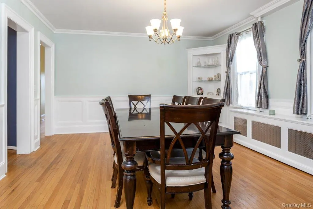Dining area featuring ornamental molding, a chandelier, light hardwood / wood-style flooring, and radiator heating unit Dining area featuring ornamental molding, a chandelier, light hardwood / wood-style flooring, and radiator heating unit