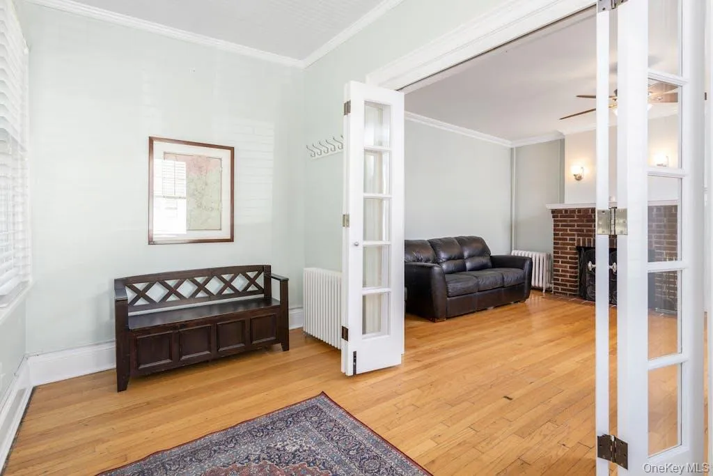 Enclosed porch entrance with radiator heating unit, hardwood flooring, and ornamental molding, French Doors to living room Enclosed porch entrance with radiator heating unit, hardwood flooring, and ornamental molding, French Doors to living room
