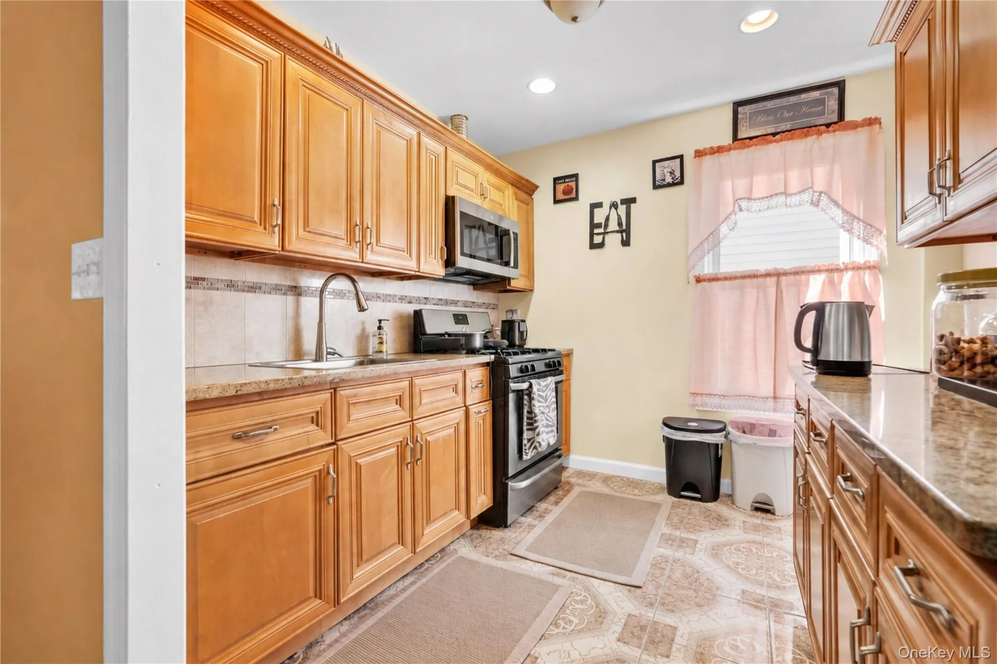 Kitchen featuring wood-finish cabinetry, stone-finish countertops, and a tiled backsplash Kitchen featuring wood-finish cabinetry, stone-finish countertops, and a tiled backsplash
