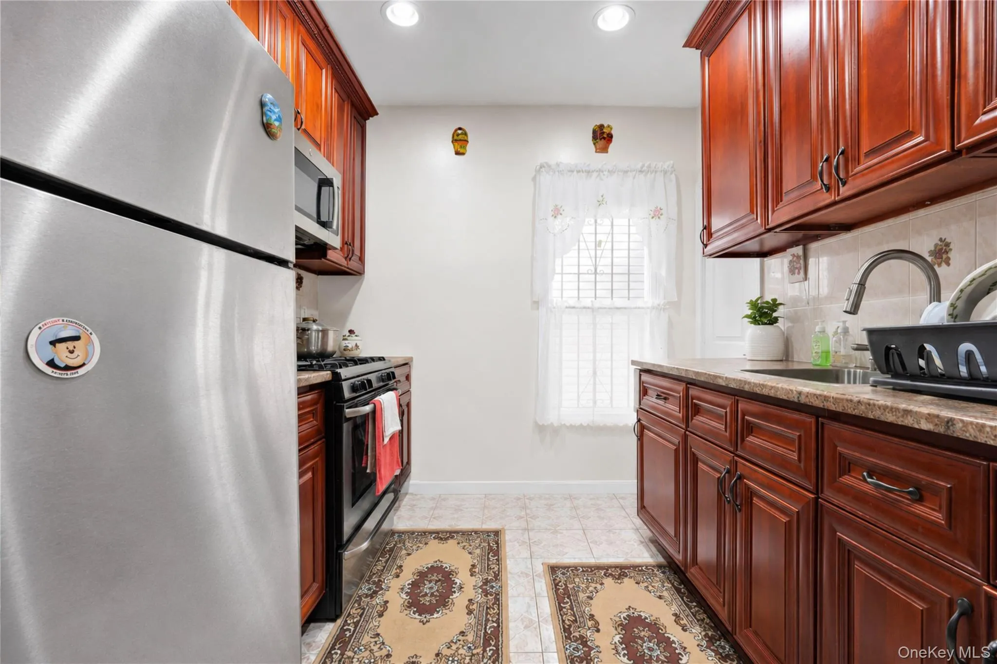 Kitchen featuring wood cabinetry, stainless steel appliances, and a tiled backsplash Kitchen featuring wood cabinetry, stainless steel appliances, and a tiled backsplash