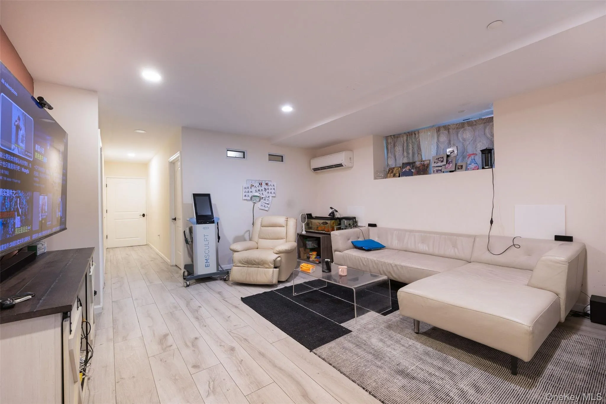 Living area featuring a wall unit AC, light wood-type flooring, and recessed lighting Living area featuring a wall unit AC, light wood-type flooring, and recessed lighting