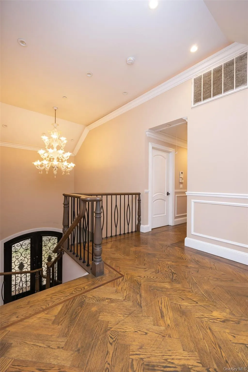 Hallway with an upstairs landing, a chandelier, crown molding, lofted ceiling, and french doors Hallway with an upstairs landing, a chandelier, crown molding, lofted ceiling, and french doors
