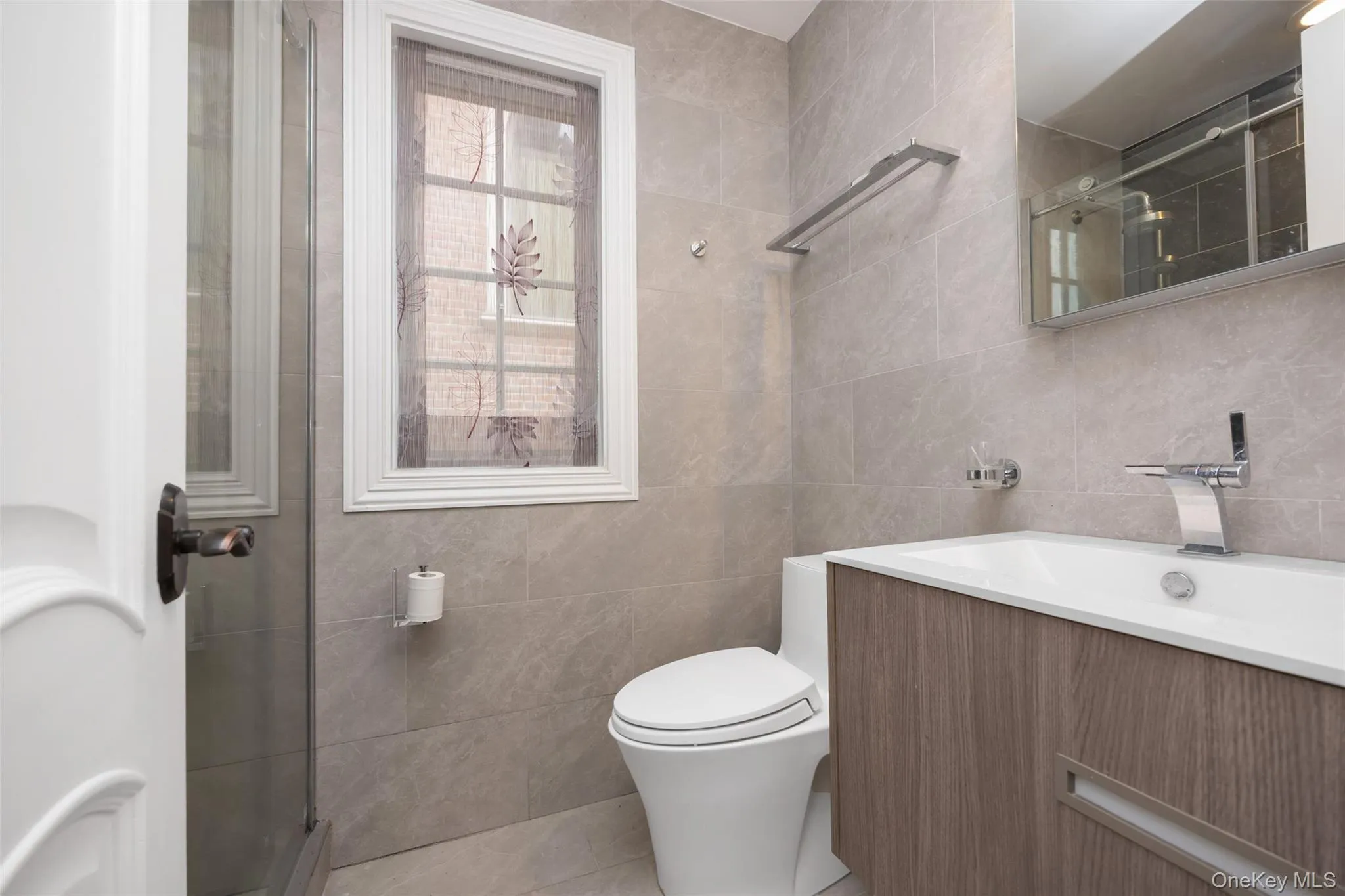 Bathroom featuring tile walls, an enclosed shower, toilet, vanity, and tile patterned floors Bathroom featuring tile walls, an enclosed shower, toilet, vanity, and tile patterned floors