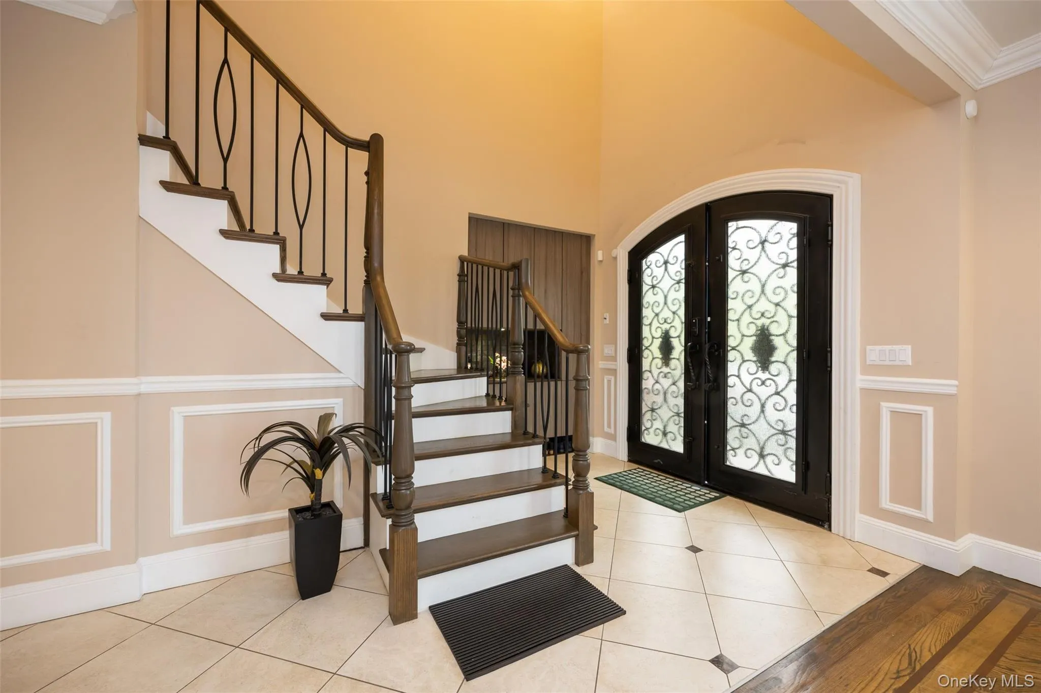 Tiled foyer featuring french doors, stairway, arched walkways, baseboards, and ornamental molding Tiled foyer featuring french doors, stairway, arched walkways, baseboards, and ornamental molding