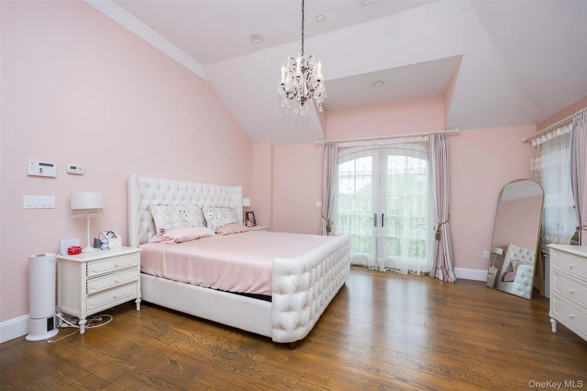 Bedroom with vaulted ceiling, a chandelier, dark wood-style floors, baseboards, and crown molding Bedroom with vaulted ceiling, a chandelier, dark wood-style floors, baseboards, and crown molding