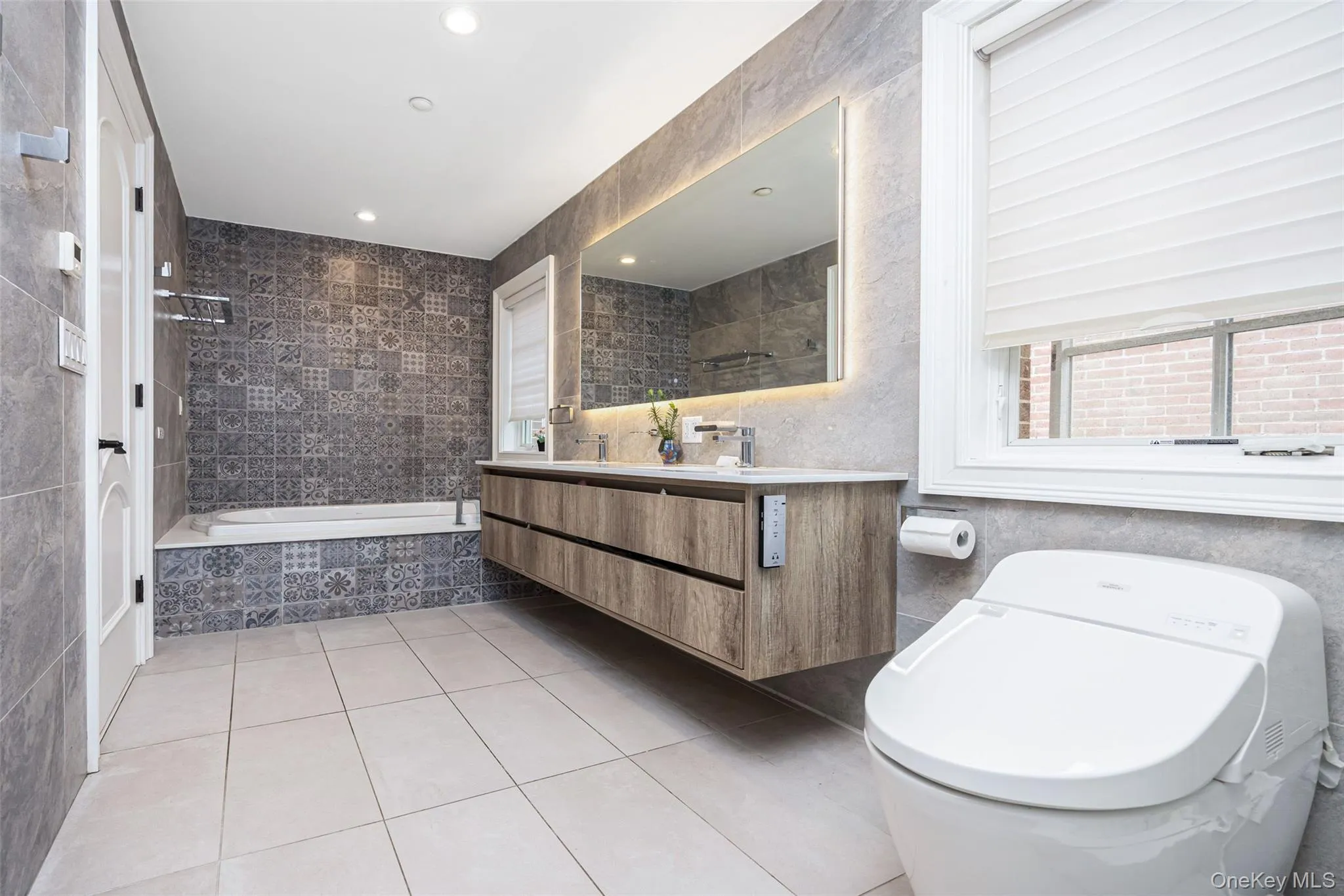 Full bathroom featuring tile patterned flooring, tile walls, tiled bath, toilet, and vanity Full bathroom featuring tile patterned flooring, tile walls, tiled bath, toilet, and vanity