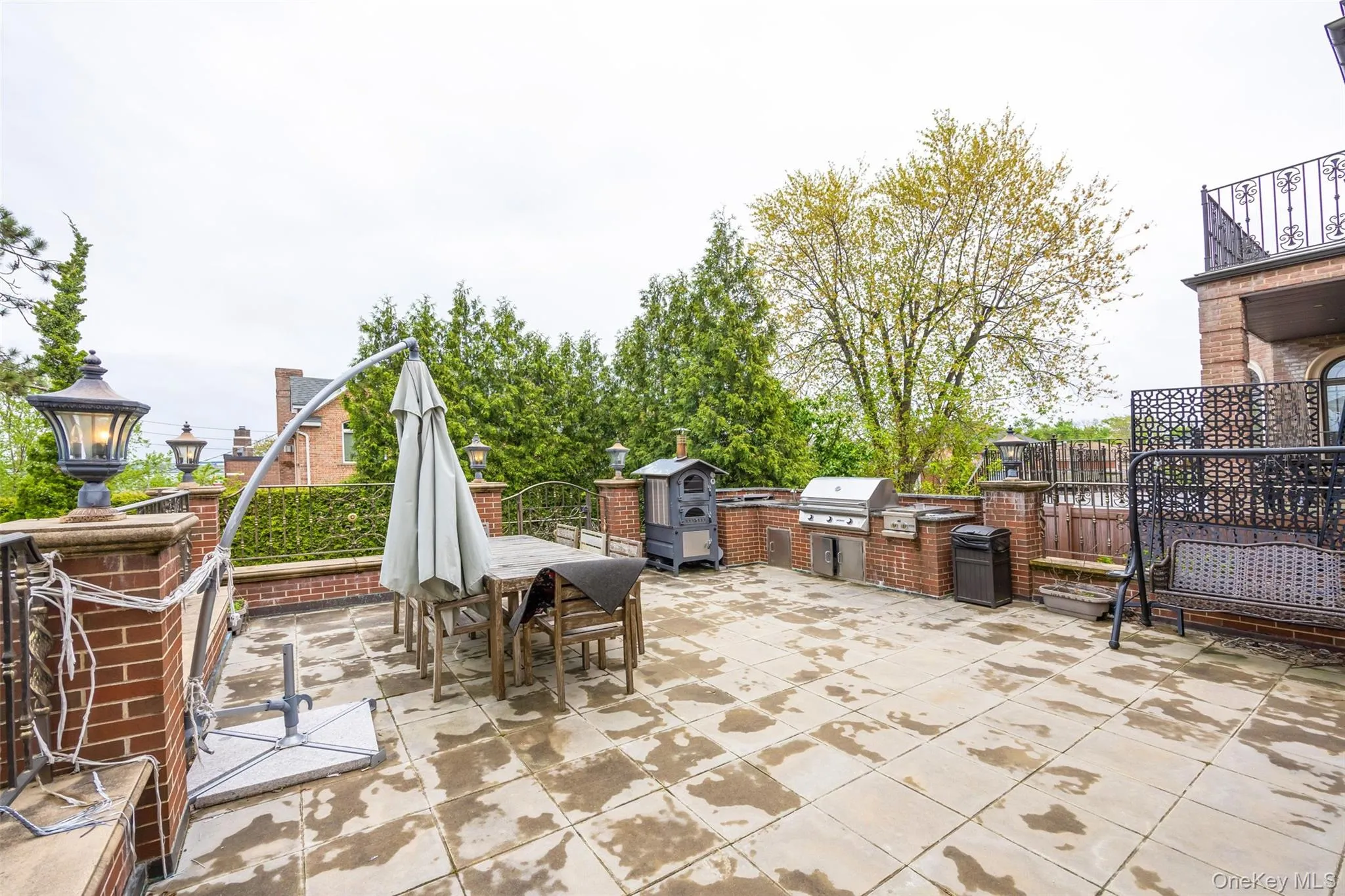 View of patio with exterior kitchen, outdoor dining space, grilling area, fence, and a balcony View of patio with exterior kitchen, outdoor dining space, grilling area, fence, and a balcony