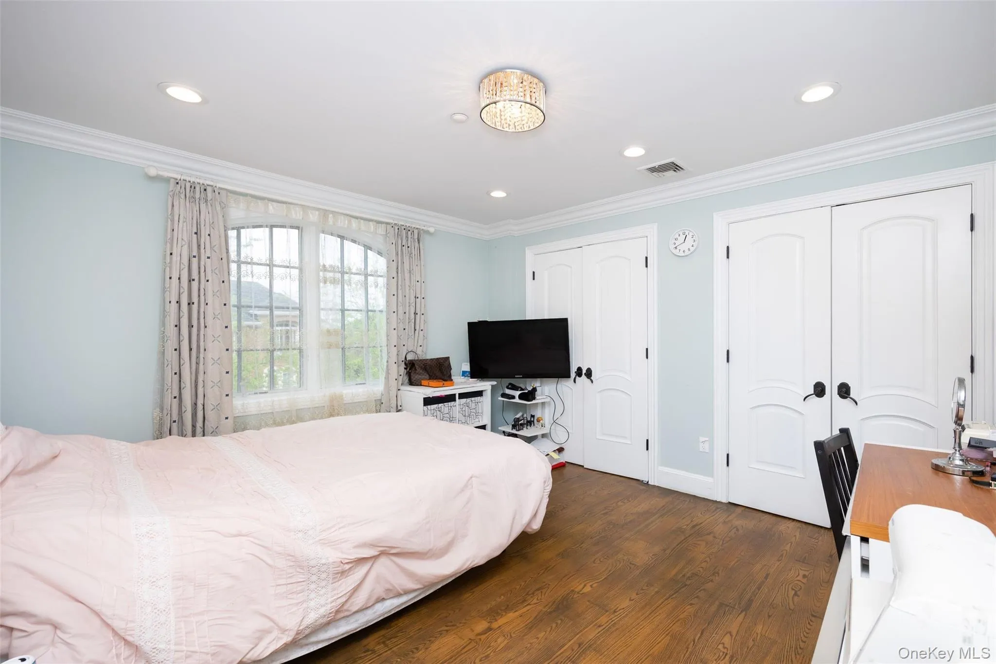 Bedroom featuring two closets, dark wood finished floors, recessed lighting, crown molding, and baseboards Bedroom featuring two closets, dark wood finished floors, recessed lighting, crown molding, and baseboards