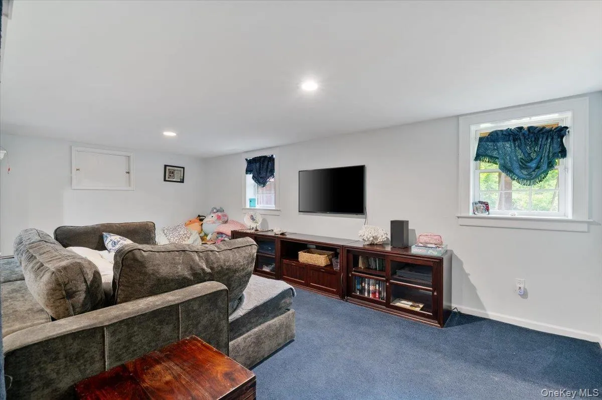 Entertainment room featuring a built-in media console, recessed lighting, and a wall-mounted television Entertainment room featuring a built-in media console, recessed lighting, and a wall-mounted television
