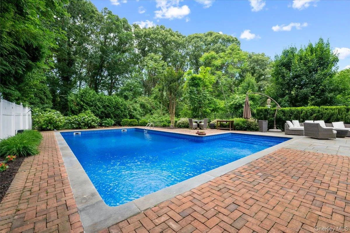 In-ground swimming pool with a surrounding brick paver patio, stone coping, and mature perimeter landscaping In-ground swimming pool with a surrounding brick paver patio, stone coping, and mature perimeter landscaping