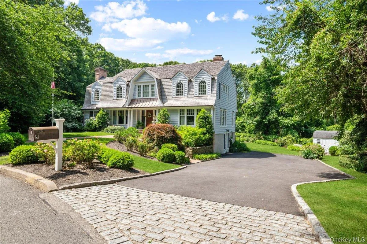 Traditional-style residence featuring light blue siding, a gambrel roof, and multiple dormer windows Traditional-style residence featuring light blue siding, a gambrel roof, and multiple dormer windows