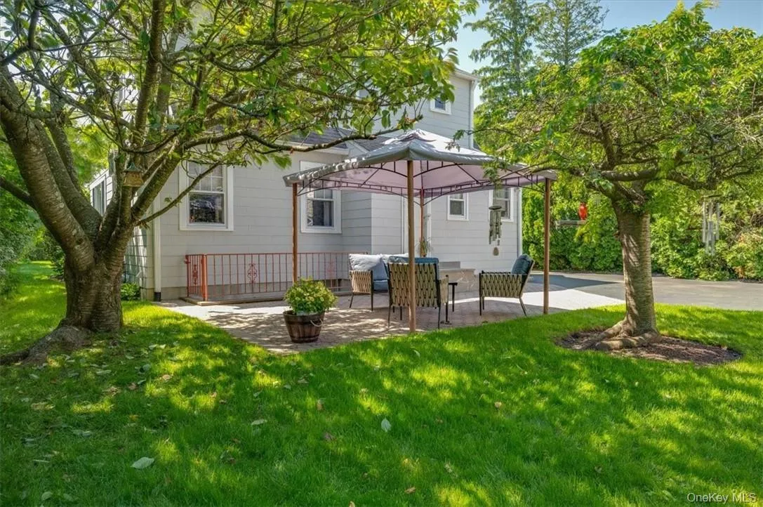 Expansive backyard featuring a paver patio with a gazebo, surrounded by mature trees and a vibrant lawn Expansive backyard featuring a paver patio with a gazebo, surrounded by mature trees and a vibrant lawn