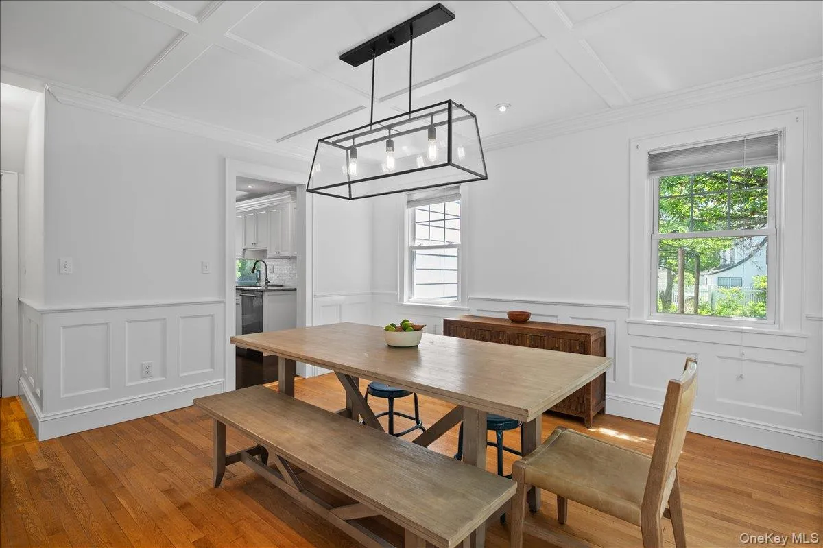 Dining area featuring wood-finish flooring, white wainscoting, and a coffered ceiling Dining area featuring wood-finish flooring, white wainscoting, and a coffered ceiling