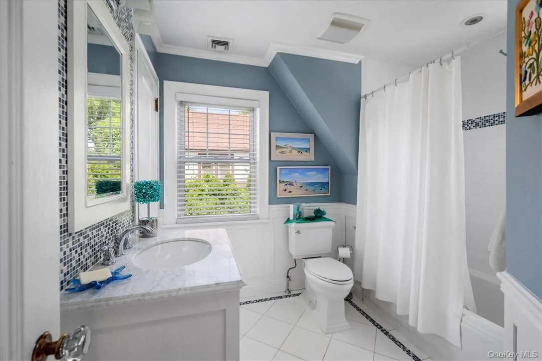 Full bathroom featuring shower / bath combination with curtain, toilet, tile floors, and large vanity Full bathroom featuring shower / bath combination with curtain, toilet, tile floors, and large vanity