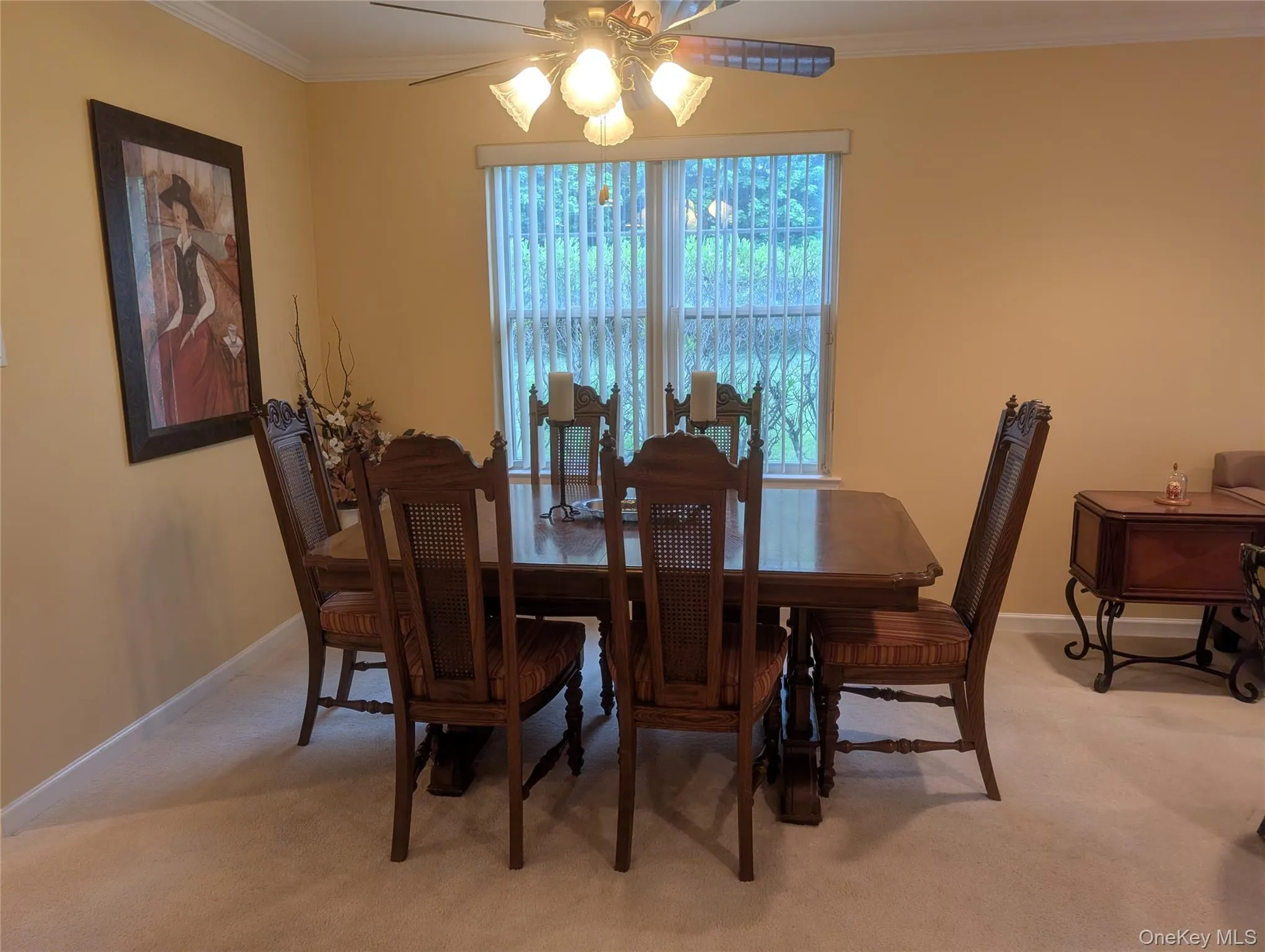 Dining area featuring a ceiling fan with light fixture, crown molding, and windows with vertical blinds Dining area featuring a ceiling fan with light fixture, crown molding, and windows with vertical blinds