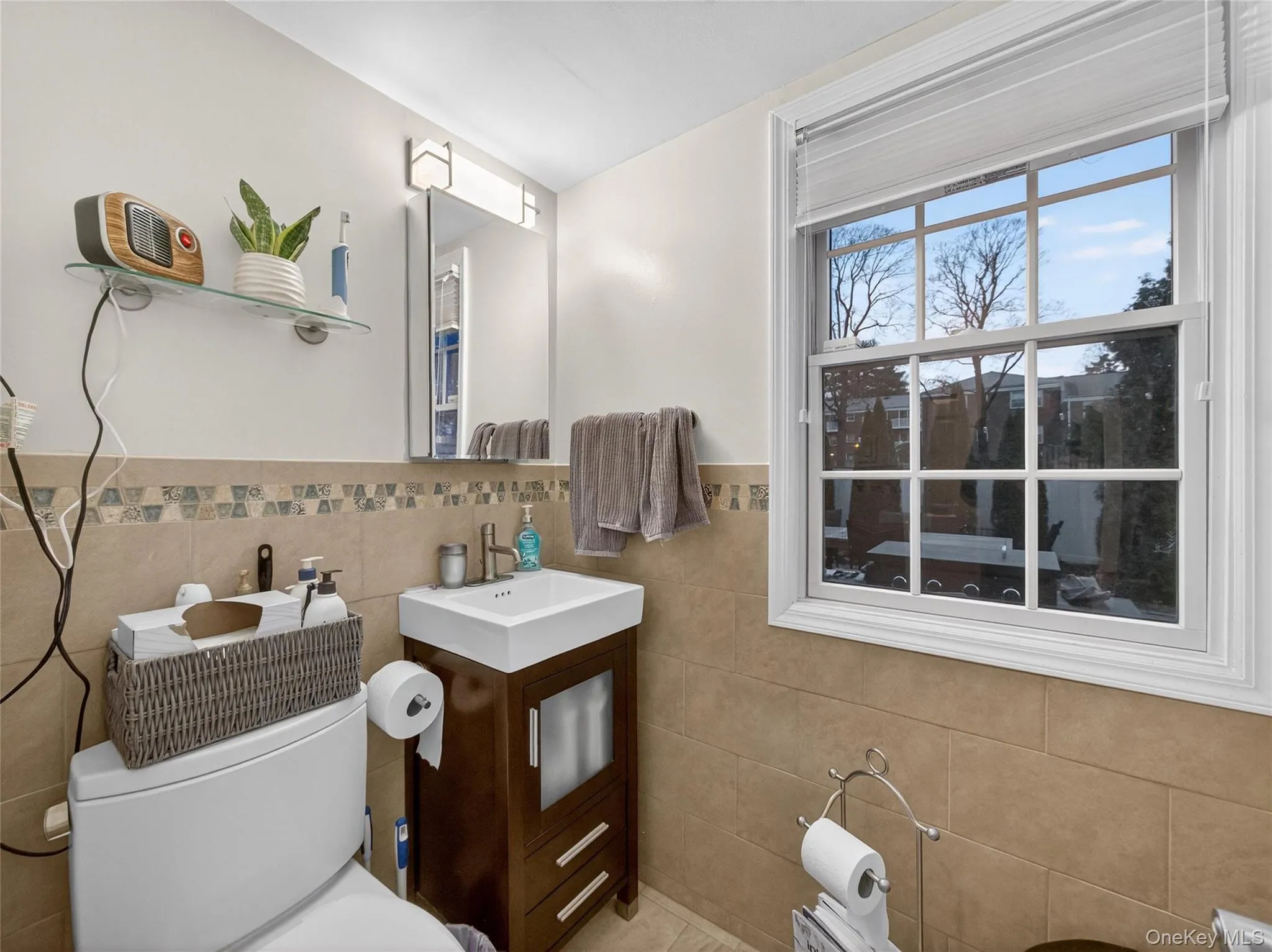 Half bathroom featuring vanity, tile walls, and a wainscoted wall Half bathroom featuring vanity, tile walls, and a wainscoted wall