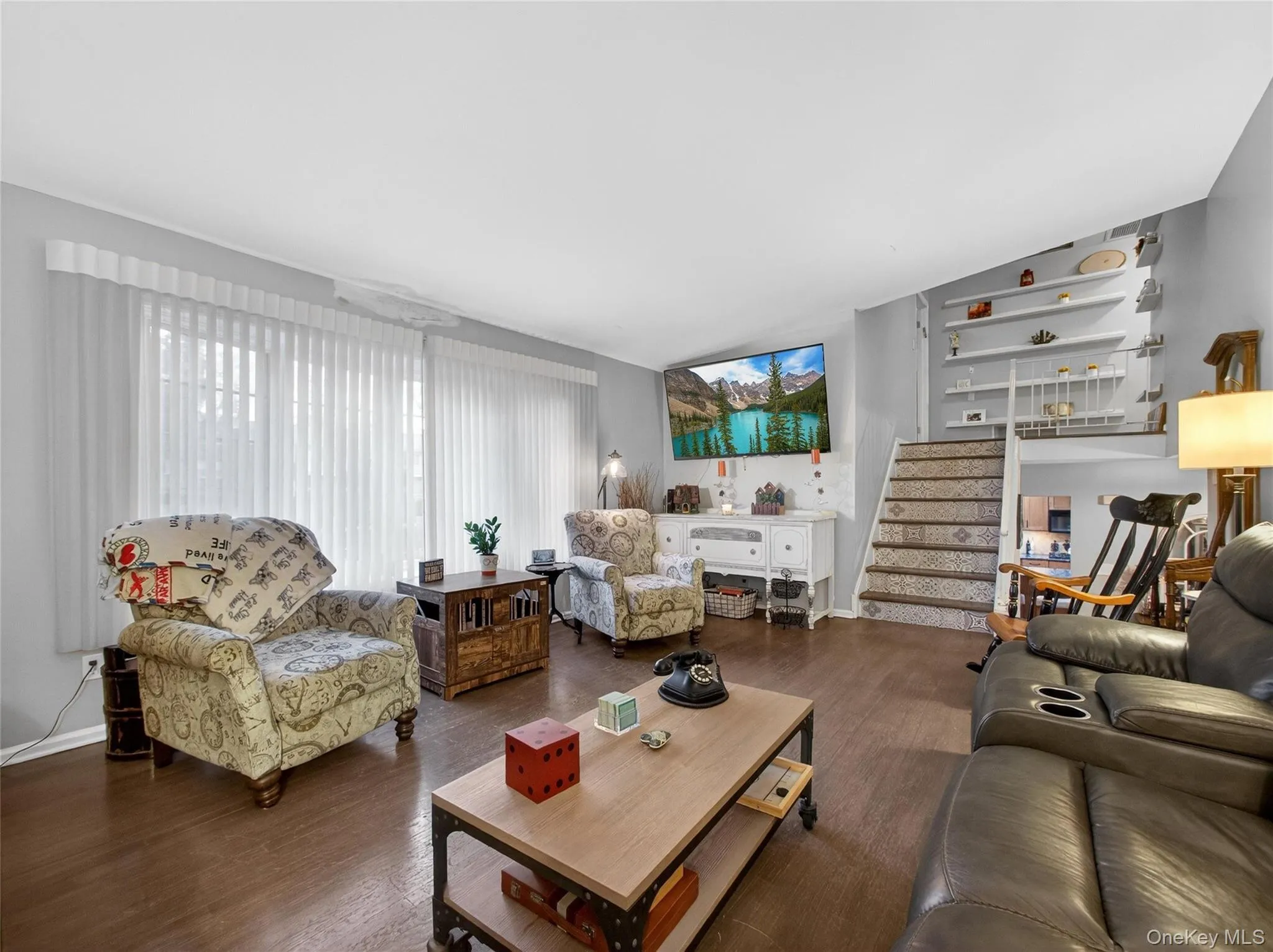 Living room featuring wood finished floors, stairway, and lofted ceiling Living room featuring wood finished floors, stairway, and lofted ceiling