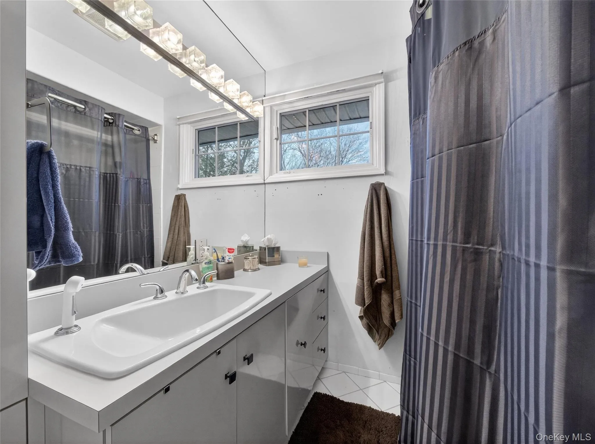 Bathroom featuring curtained shower, vanity, and light tile patterned flooring Bathroom featuring curtained shower, vanity, and light tile patterned flooring