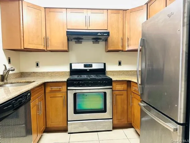 Kitchen with stainless stee; appliances, brown cabinetry, granite countertops and under cabinet range hood Kitchen with stainless stee; appliances, brown cabinetry, granite countertops and under cabinet range hood