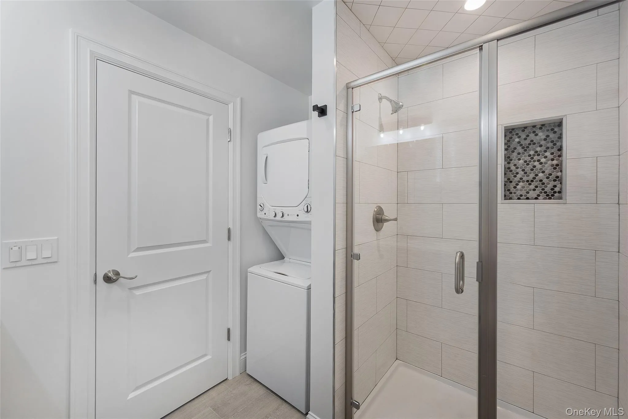 Bathroom featuring stacked washer / dryer and an enclosed shower Bathroom featuring stacked washer / dryer and an enclosed shower