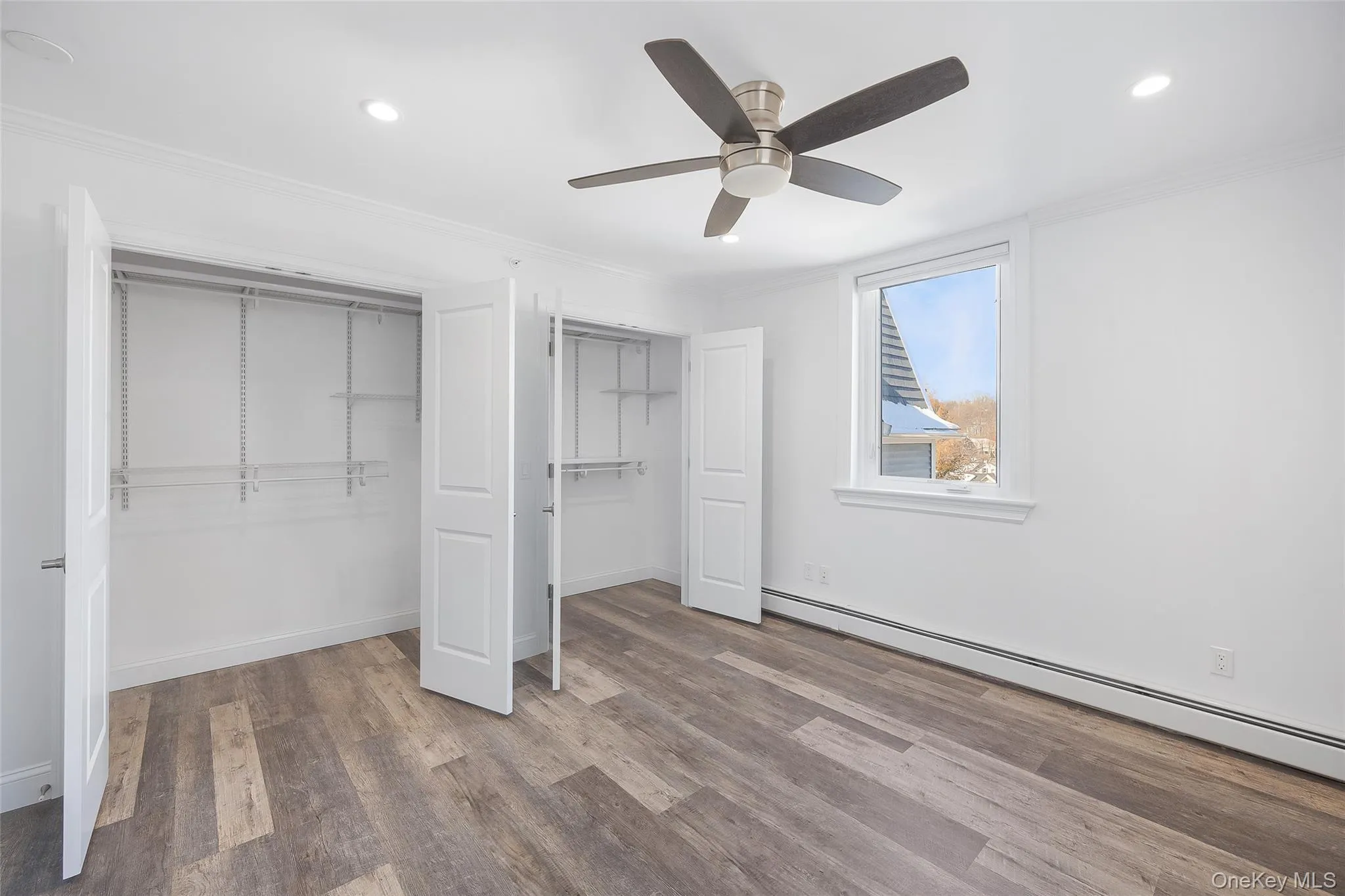 Unfurnished bedroom featuring ceiling fan, a baseboard radiator, hardwood / wood-style flooring, and crown molding Unfurnished bedroom featuring ceiling fan, a baseboard radiator, hardwood / wood-style flooring, and crown molding
