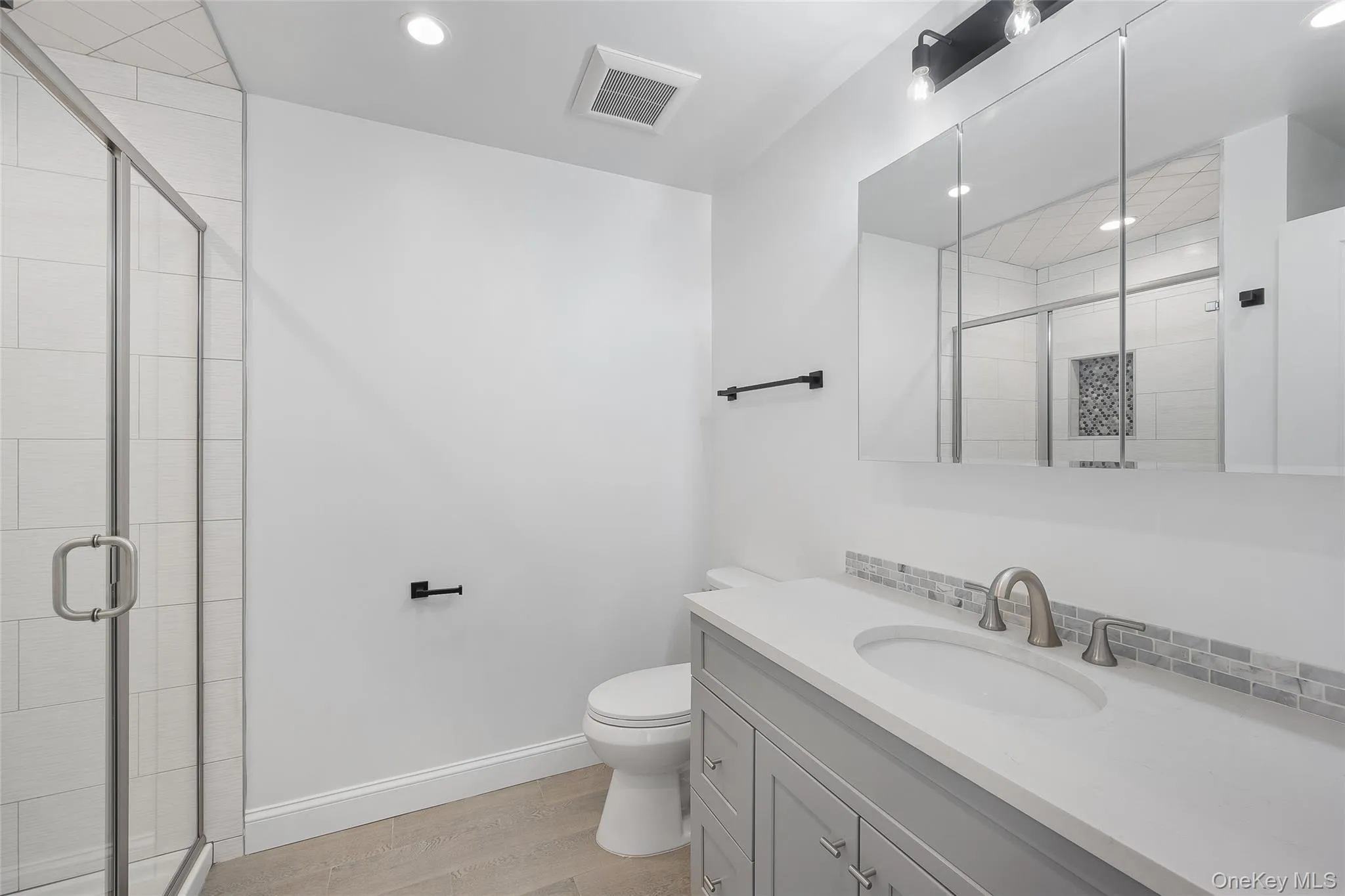 Bathroom with hardwood / wood-style flooring, toilet, a shower with shower door, and vanity Bathroom with hardwood / wood-style flooring, toilet, a shower with shower door, and vanity
