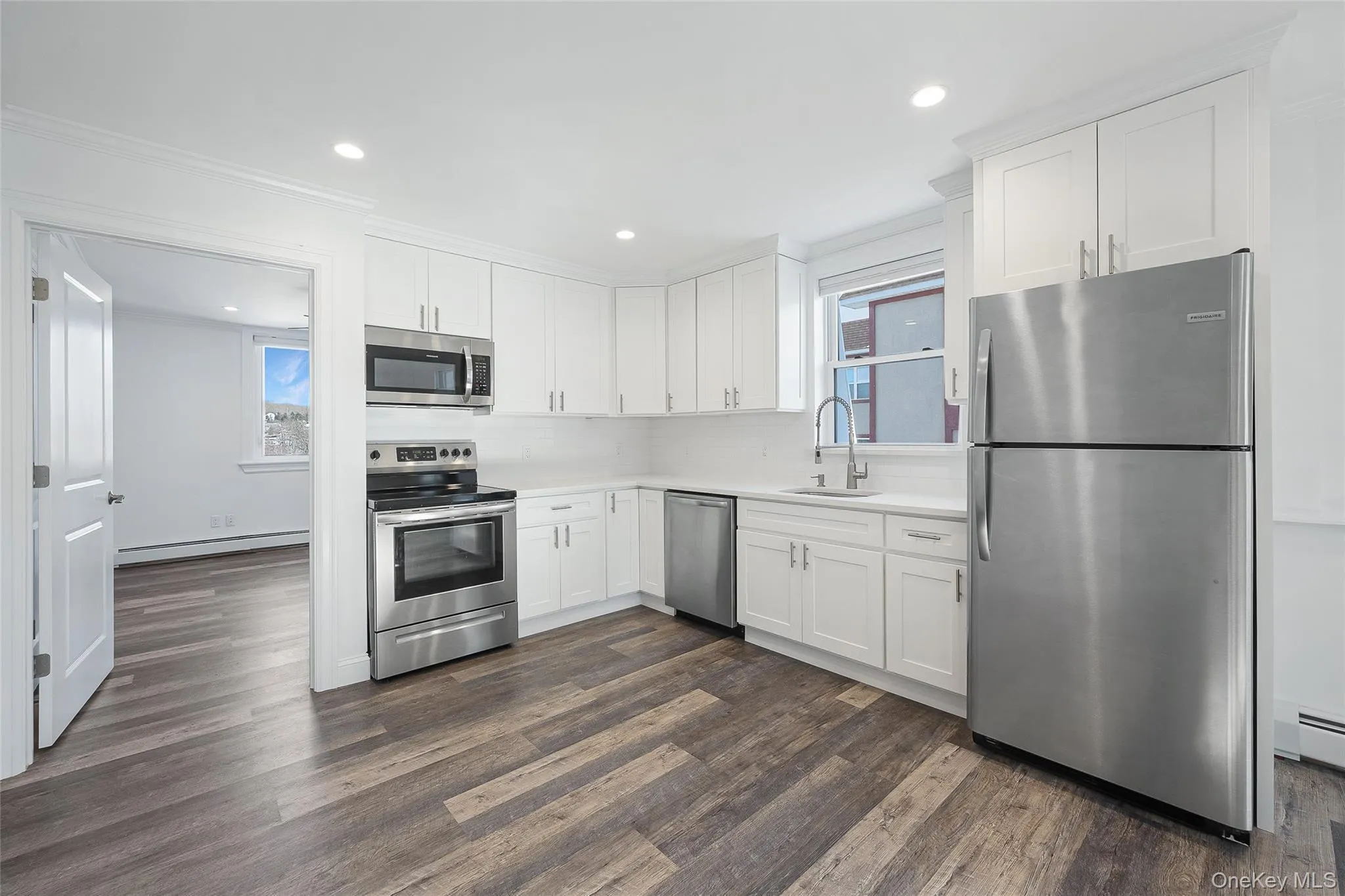 Kitchen featuring white cabinetry, stainless steel appliances, sink, dark hardwood / wood-style floors, and ornamental molding Kitchen featuring white cabinetry, stainless steel appliances, sink, dark hardwood / wood-style floors, and ornamental molding