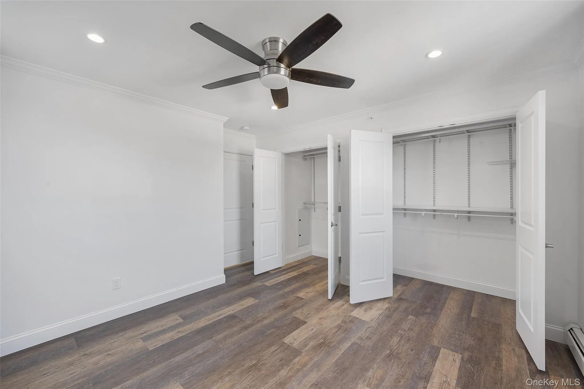 Unfurnished bedroom featuring dark hardwood / wood-style floors, a baseboard heating unit, ceiling fan, and ornamental molding Unfurnished bedroom featuring dark hardwood / wood-style floors, a baseboard heating unit, ceiling fan, and ornamental molding