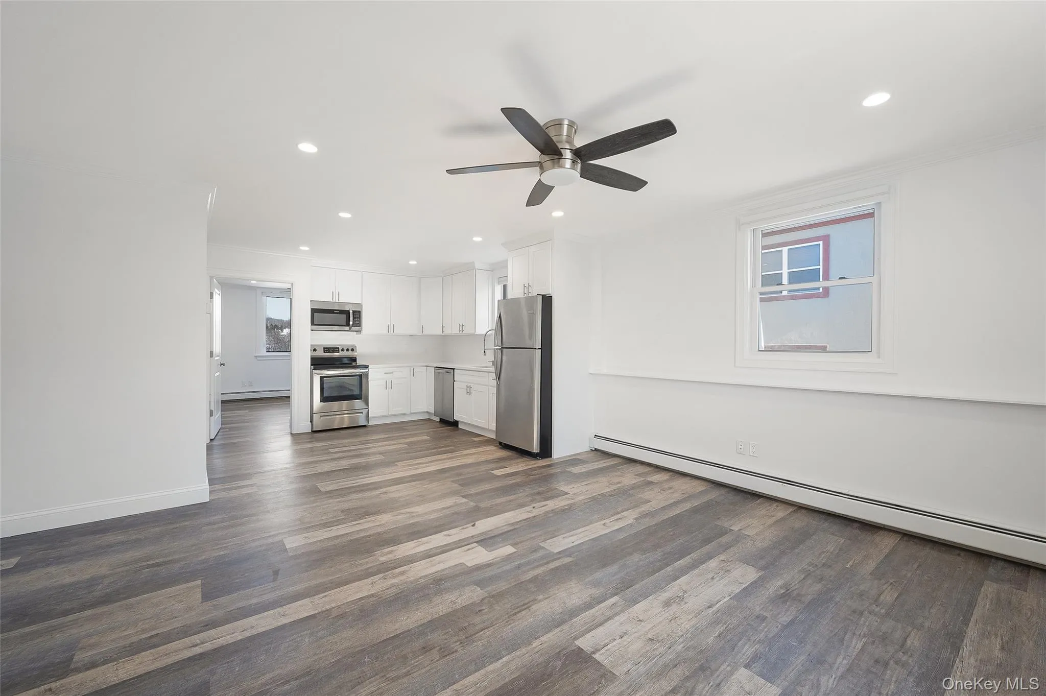 Unfurnished living room with ceiling fan, dark hardwood / wood-style floors, crown molding, and baseboard heating Unfurnished living room with ceiling fan, dark hardwood / wood-style floors, crown molding, and baseboard heating