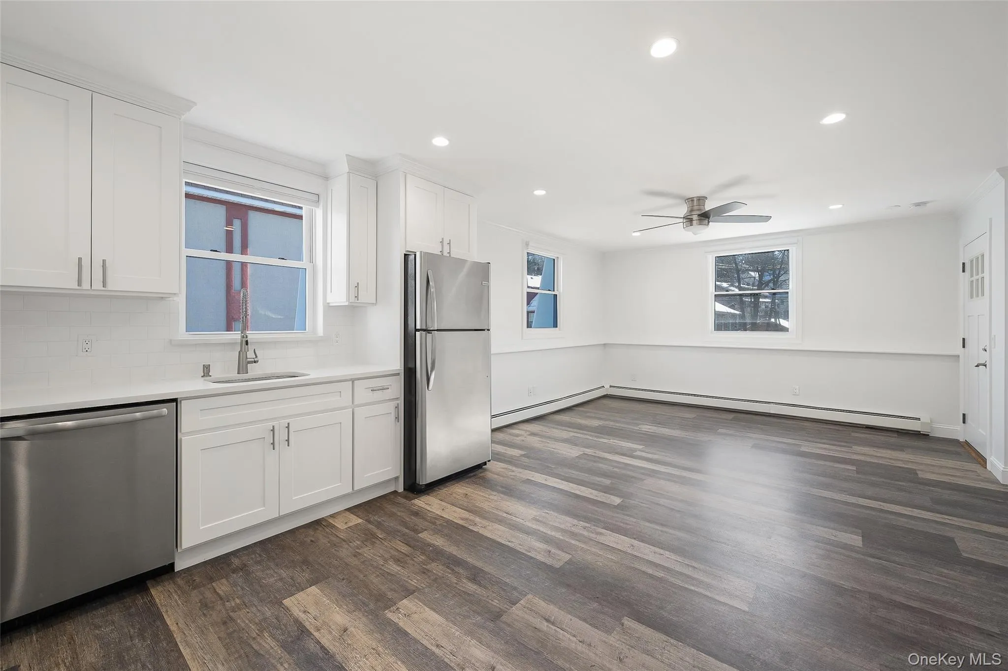 Kitchen with sink, white cabinetry, a baseboard heating unit, and stainless steel appliances Kitchen with sink, white cabinetry, a baseboard heating unit, and stainless steel appliances